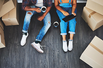 Image showing Tablet, coffee and couple moving with boxes planning their new house together on living room floor. Technology, caffeine and top view of man and woman doing property research on mobile in their home.