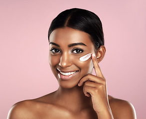 Image showing Happy, skincare and face of woman with cream in studio isolated on a pink background. Dermatology, creme cosmetics and portrait of happy Indian female model apply moisturizer lotion for healthy skin.