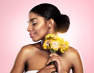 Image showing Woman, face and flowers for skincare in studio, pink background and eco friendly makeup cosmetics. African model, natural beauty and yellow daisy plants for sustainability, floral blossom and perfume