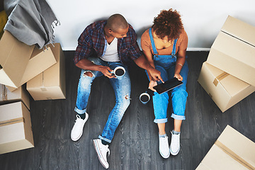 Image showing Digital tablet, coffee and couple with boxes planning their new apartment together on the floor. Technology, caffeine and top view of man and woman doing property research on mobile moving in a home.