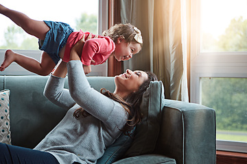 Image showing Happy, mom and lifting girl on sofa in home living room and relax, bonding and quality time together or mother, love and family happiness. Child, mommy and playing game on couch in house with smile