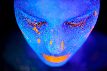 Image showing Art, facial and woman with neon paint in studio for fantasy, creative or psychedelic aesthetic. Illusion, creativity and female model with glitter and bright color facial cosmetics by dark background