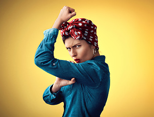 Image showing Pinup girl, strong and flexing muscle portrait in studio for support, women power and fashion. Angry female person show bicep on yellow background for motivation, freedom and retro or vintage style