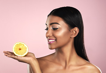 Image showing Skincare, face and smile of woman with an orange in studio isolated on pink background. Fruit, natural cosmetics and Indian female model holding food for healthy diet, nutrition or vitamin c to detox