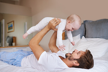Image showing Father, on bed and holding his baby girl up in the air or playful daughter and having fun in the bedroom feeling happy. Parent, kid and dad bonding or carefree and excited together in the house