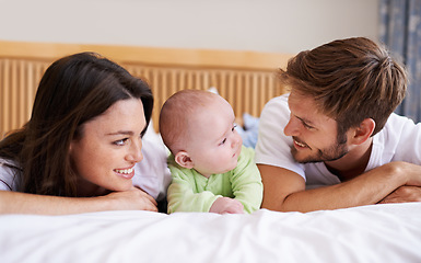 Image showing Happy family, mother and father with baby on bed for love, care and fun quality time together at home. Parents, cute newborn child and bonding to relax in bedroom for support, nurture and happiness