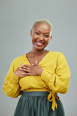 Image showing Portrait, thank you and hands on chest of happy woman in studio with love sign on wall background. Face, smile and hand on heart by female person showing gratitude, kindness and self care or honesty