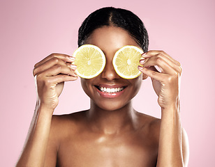 Image showing Happy woman, beauty and eyes with lemon in studio, pink background and vitamin c benefits. Face, african model and fun with citrus fruits for natural skincare, vegan cosmetics and facial aesthetic