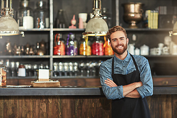 Image showing Happy, crossed arms and portrait of male barista standing by the counter in his startup cafeteria. Smile, success and young man small business owner with confidence in coffee shop or restaurant.