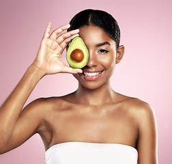 Image showing Avocado, portrait and beauty of woman in studio, pink background and aesthetic glow. Happy african model, natural skincare and fruit for sustainable cosmetics, vegan dermatology and facial benefits