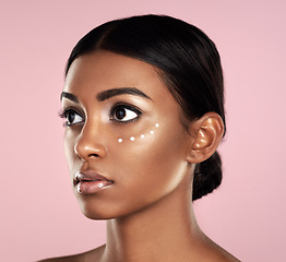 Image showing Thinking, skincare or beauty of woman with eye cream in studio isolated on pink background. Dermatology, creme cosmetics and serious Indian female model with moisturizer retinol for healthy face skin