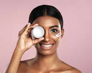 Image showing Face, skincare and woman with cream container in studio isolated on a pink background. Portrait, dermatology cosmetics and happy Indian female model with lotion, moisturizer product or beauty creme.