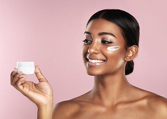 Image showing Skincare, smile and woman with cream container in studio isolated on a pink background. Product, dermatology creme and Indian female model holding lotion, moisturizer and cosmetics for healthy skin.