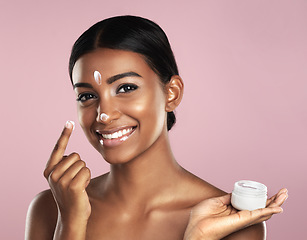 Image showing Skincare, face and woman with cream container in studio isolated on a pink background. Product, dermatology creme and portrait of happy Indian female model apply lotion, moisturizer and cosmetics.