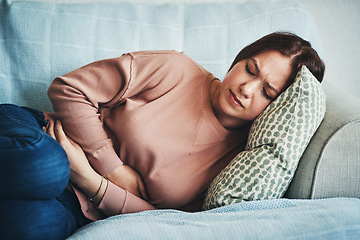 Image showing Stomach ache, pain and woman on home sofa with menstrual or period cramps in lounge. Sick, abdomen or colon problem of a female person with hands on tummy for constipation, digestion or virus