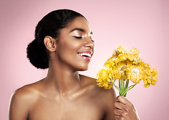 Image showing Happy woman, yellow flowers and natural skincare in studio, pink background and eco friendly makeup cosmetics. African model, beauty and smile with daisy plants, happiness and glow of floral facial