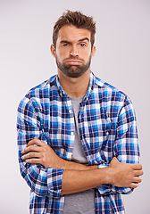 Image showing Frustrated, tired and portrait of a man with arms crossed in a studio feeling annoyed and bored. Isolated, white background and male model with upset face and grumpy with casual fashion and doubt