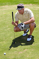 Image showing Mature man, golf and focus on ball on the course for professional game, sports or hobby. Focus, looking and a golfer lining up putt on grass with a club during a competition or match for recreation