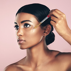 Image showing Face, skincare serum and woman in studio isolated on a pink background. Dermatology, cosmetics and Indian model with hyaluronic acid, essential oil or vitamin c dropper for healthy skin and beauty.