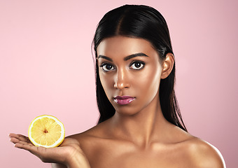 Image showing Face, skincare and woman with lemon in studio isolated on pink background. Fruit, serious and portrait of Indian female model with citrus food for healthy skin, vitamin c and detox diet for nutrition