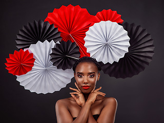 Image showing Face, beauty and black woman with origami fans in studio isolated on a dark background. Serious portrait, makeup cosmetics and skincare of female model with traditional Japanese paper art for culture