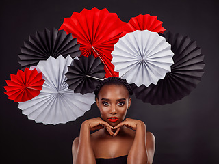 Image showing Portrait, makeup and black woman with origami fans in studio isolated on a dark background. Serious face, beauty cosmetics and skincare of female model with traditional Japanese paper art for culture