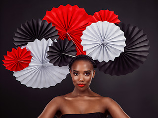 Image showing Face, makeup and black woman with origami fans in studio isolated on a dark background. Serious portrait, beauty cosmetics and skincare of female model with traditional Japanese paper art for culture