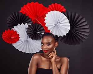 Image showing Face, beauty and black woman with origami fans in studio isolated on a dark background. Portrait, makeup cosmetics and skincare of female model with traditional Japanese paper art for fashion hat.