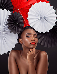 Image showing Face, makeup and black woman with origami fans in studio isolated on a dark background. Portrait, beauty cosmetics and skincare of serious female model with traditional Japanese paper hat for art.