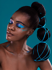 Image showing Face, beauty and makeup with an african woman in studio on a blue background for hair or cosmetics. Eye shadow, haircare and fashion with an attractive young female model at the salon for style