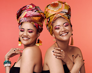 Image showing Fashion, friends and African women with beauty on orange background with cosmetics, makeup and accessories. Glamour, luxury and face of female people with exotic jewelry, traditional style and scarf