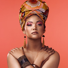 Image showing African fashion, beauty and portrait of woman on orange background with cosmetics, makeup and accessories. Glamour, model and face of female person with exotic jewelry, traditional style and scarf