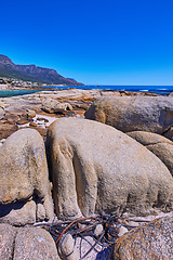 Image showing Scenic view of the rocky coastline of Camps Bay, Cape Town. Boulders in lining the ocean in the Western Cape, South Africa. Relaxing seaside views of the city of and mountains