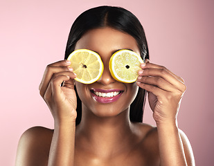 Image showing Face, skincare and smile of woman with orange slices in studio isolated on a pink background. Fruit, natural cosmetics and Indian female model holding food for healthy diet, nutrition or vitamin c.