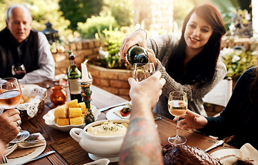 Image showing Food, pouring wine and people eating together at table to celebrate holiday, Christmas or thanksgiving. Family or friends group outdoor for lunch or dinner with alcohol, glass and bottle in summer