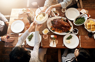 Image showing Food, people and eating together at table for holiday celebration or dinner party. Above group of family or friends hands sharing healthy lunch with chicken or turkey, vegetables and wine drinks