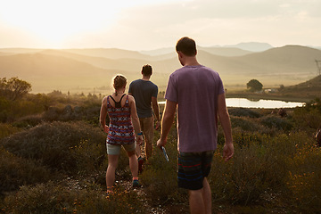 Image showing Friends hiking, walking in countryside at sunset with fitness and bonding in nature with travel and freedom. Exercise, adventure with men and woman walk through meadow or field with back view