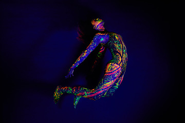 Image showing Woman, neon paint and dancer jump on dark background for creative performance, splatter texture and psychedelic fantasy. Body artist, color splash and unique glow in surreal circus on mockup studio