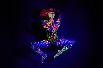 Image showing Body paint, dance and portrait of a woman in neon lighting isolated on a dark background in a studio. Creative, glow and a dancing model with psychedelic art for creativity and fluorescent abstract