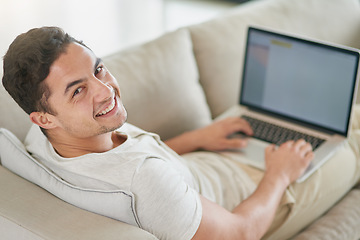 Image showing Laptop, sofa and portrait of man doing remote work in his home, house or apartment with smile and relax in living room. Couch, happy and young male person or freelancer typing a project online or web