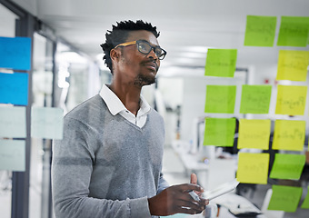 Image showing Business tablet, glass wall and black man planning, strategy or research in office workplace. Sticky notes, brainstorming and African male professional with technology for working, schedule and ideas