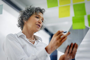 Image showing Glass wall, tablet and business woman planning, strategy and research in workplace. Sticky notes, brainstorming and senior female professional with technology for working, schedule and low angle.