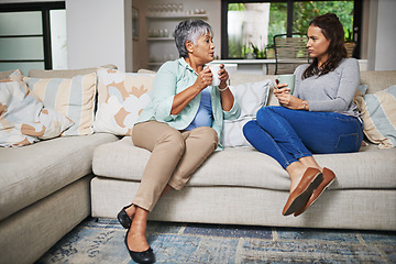 Image showing Support, coffee and mother with daughter on sofa in living room for bonding, conversation and free time. Relax, chat and discussion with women talking in family home for generations, reunion or break