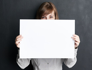 Image showing Portrait, poster and mockup with a woman in studio on a dark background for information or announcement. Branding, advertising or marketing with a young female brand ambassador holding a blank sign