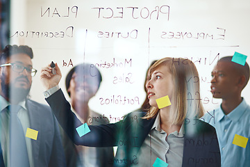 Image showing Business people, glass wall and woman writing, planning and strategy in office. Sticky notes, brainstorming ideas and group of employees working on project, schedule and collaboration for teamwork.