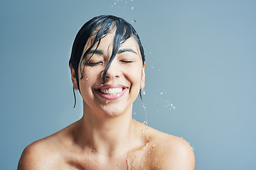 Image showing Beauty, water splash and face of woman shower on blue background for wellness, cleaning and grooming. Skincare, bathroom and happy female person for washing hair, body care and cleansing in studio