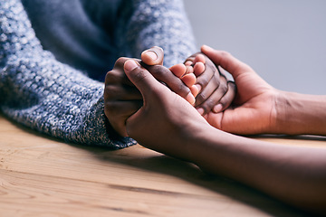 Image showing Love, support and people holding hands for unity, compassion and sympathy by a wood table. Empathy, care and couple or friends with affection in an intimate bonding moment together for grief and loss