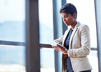 Image showing Tablet, mockup and research with a business woman leaning against a glass wall or window at the office. Technology, corporate and space with a young professional female employee working online