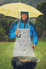 Image showing Happy man, portrait and umbrella in rain for barbecue meal, supper or dinner on the fire grill. Male person smiling for insurance, cover or protection while cooking under raining or stormy weather