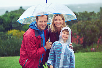 Image showing Happy, rain and portrait of a family with umbrella outdoor in nature for fun, happiness and quality time. Man, woman and boy child together with water drops and freedom while playing on vacation